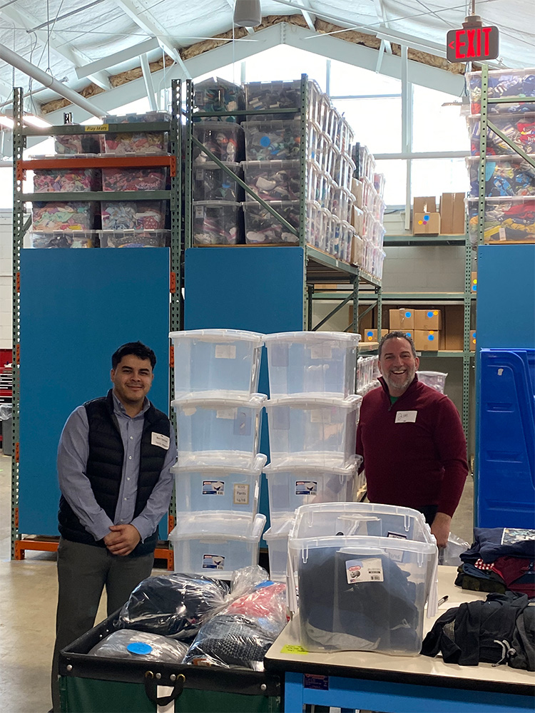 Ben and James posing for photo next to bins of clothes