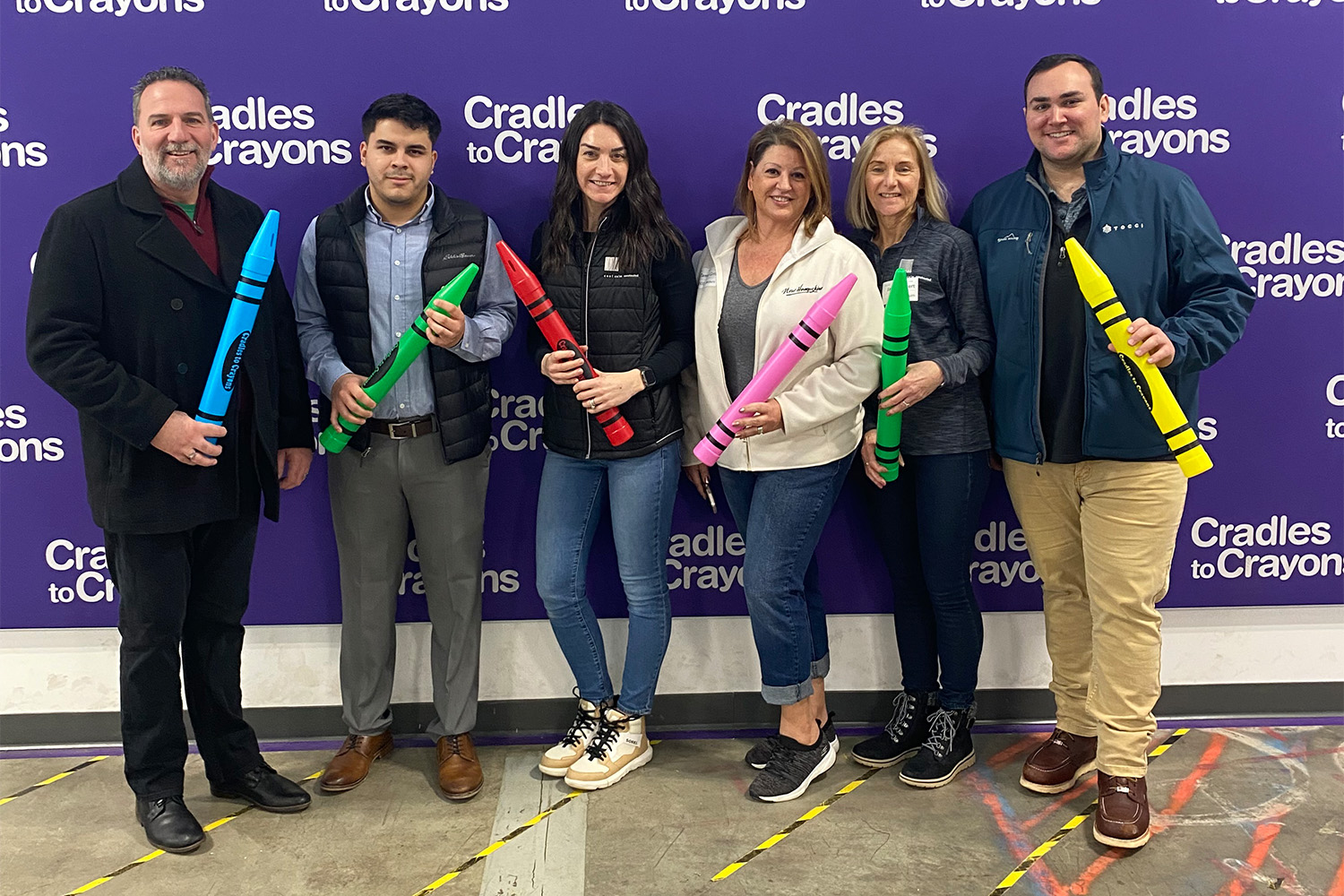 Tocci employees posing for group photo while holding big fake crayons