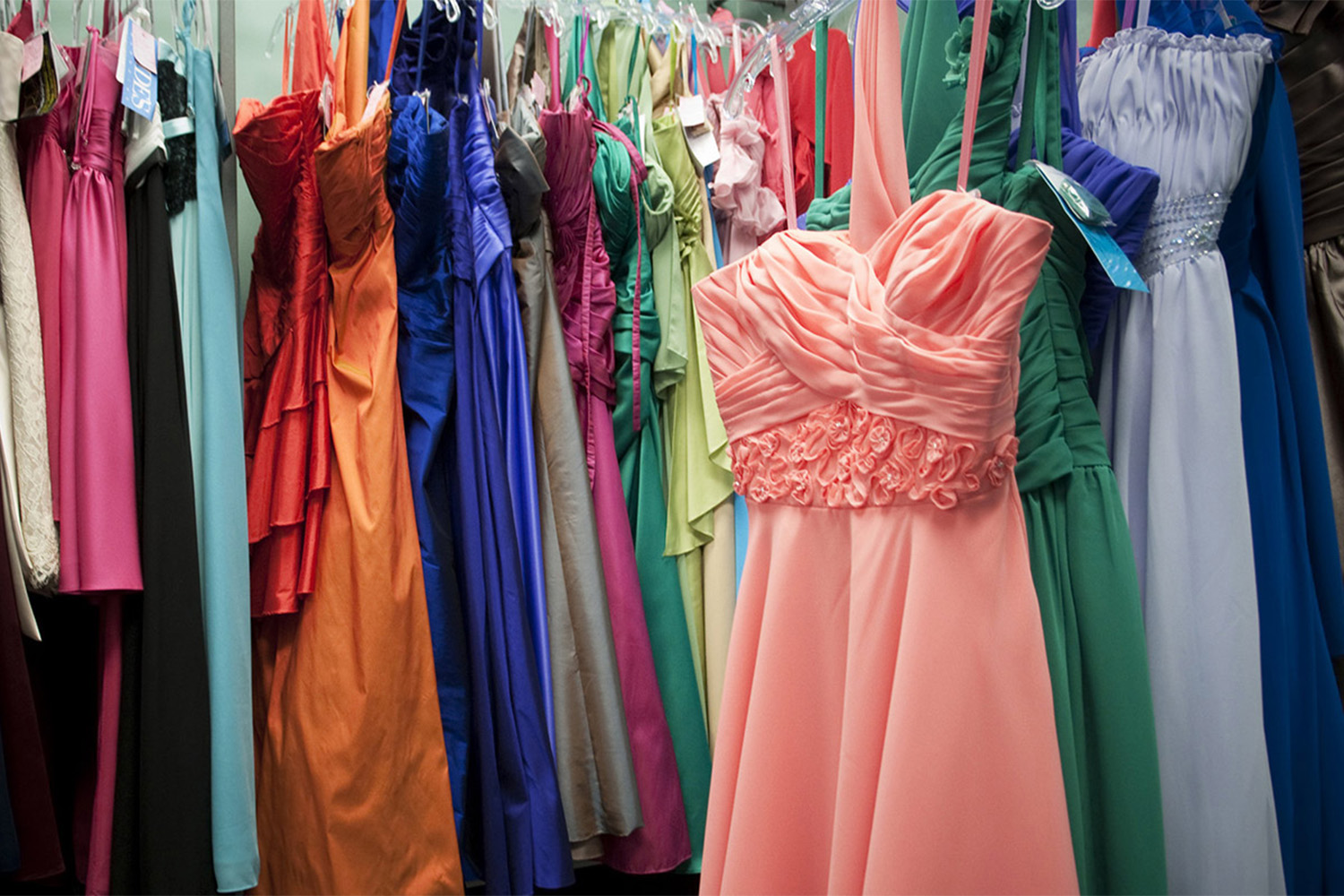 various colorful prom dresses on a clothing rack 