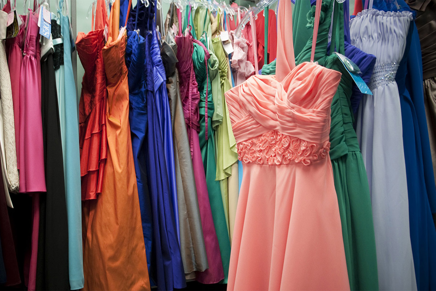 various colorful prom dresses on a clothing rack