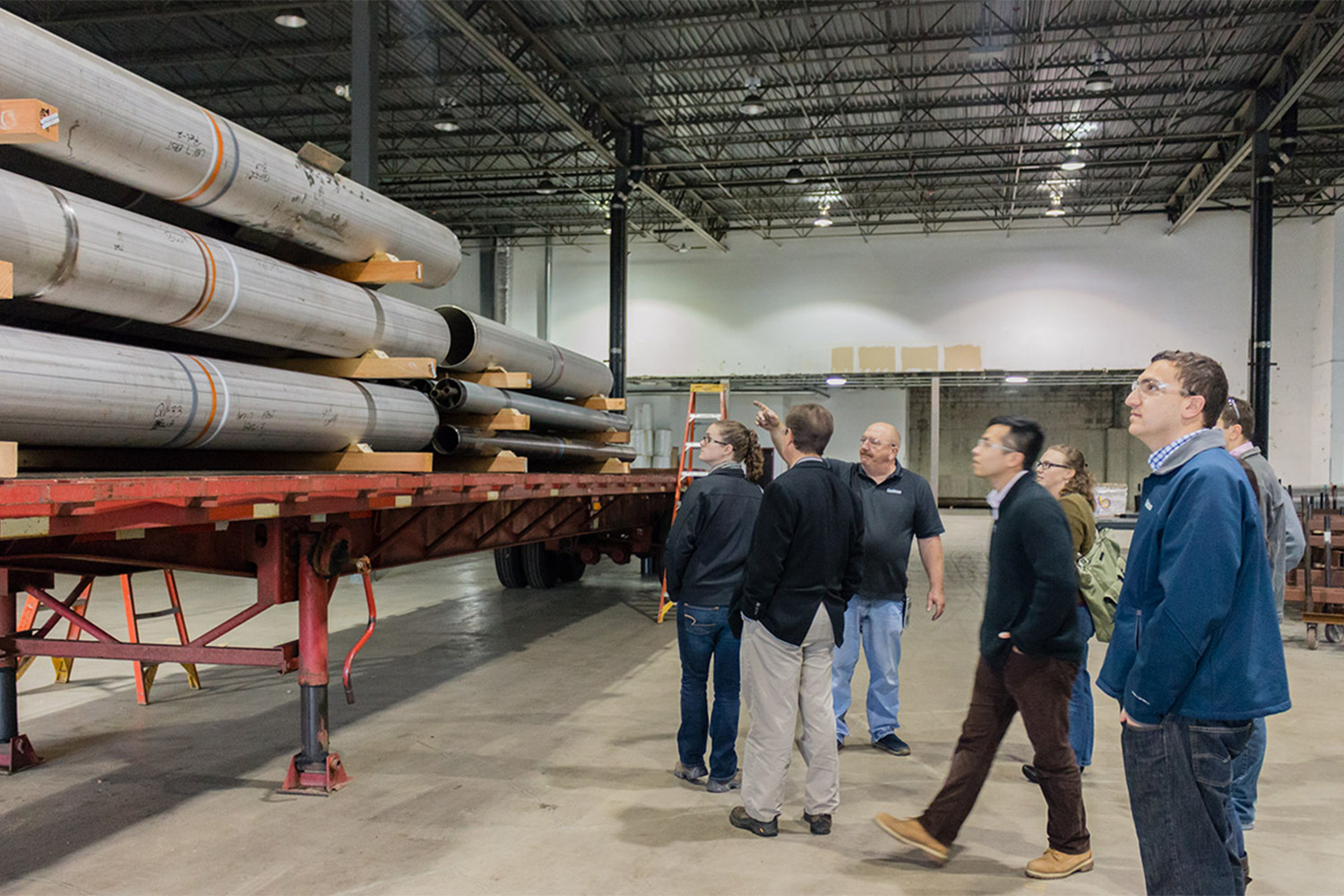 Tocci personnel look at stacks of metal beams in the workshop 