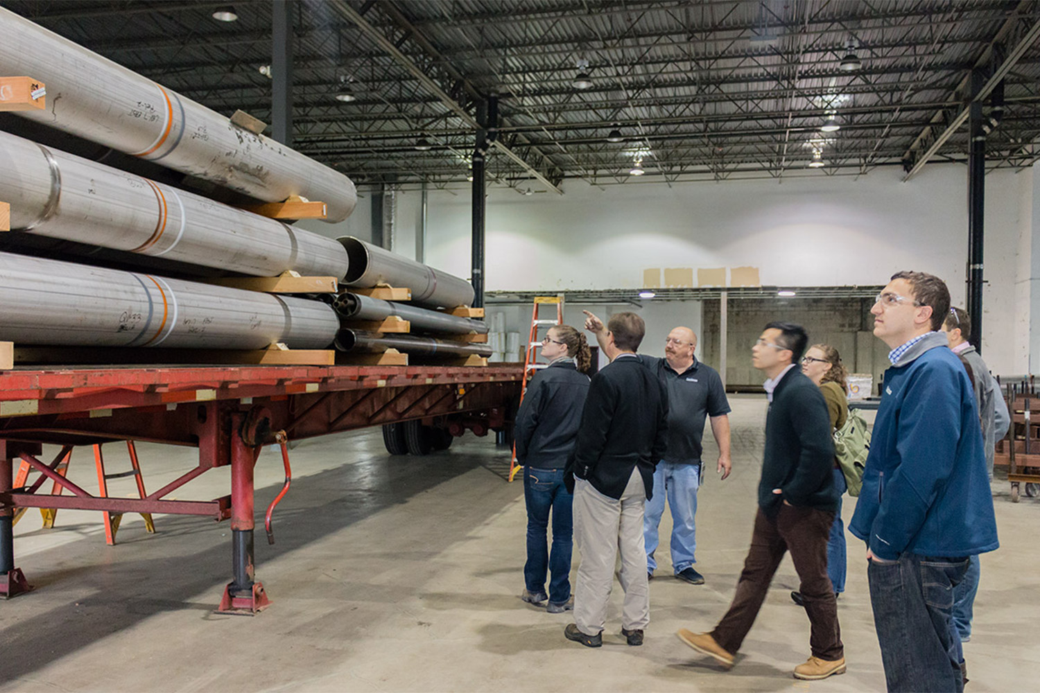 Tocci personnel look at stacks of metal beams in the workshop