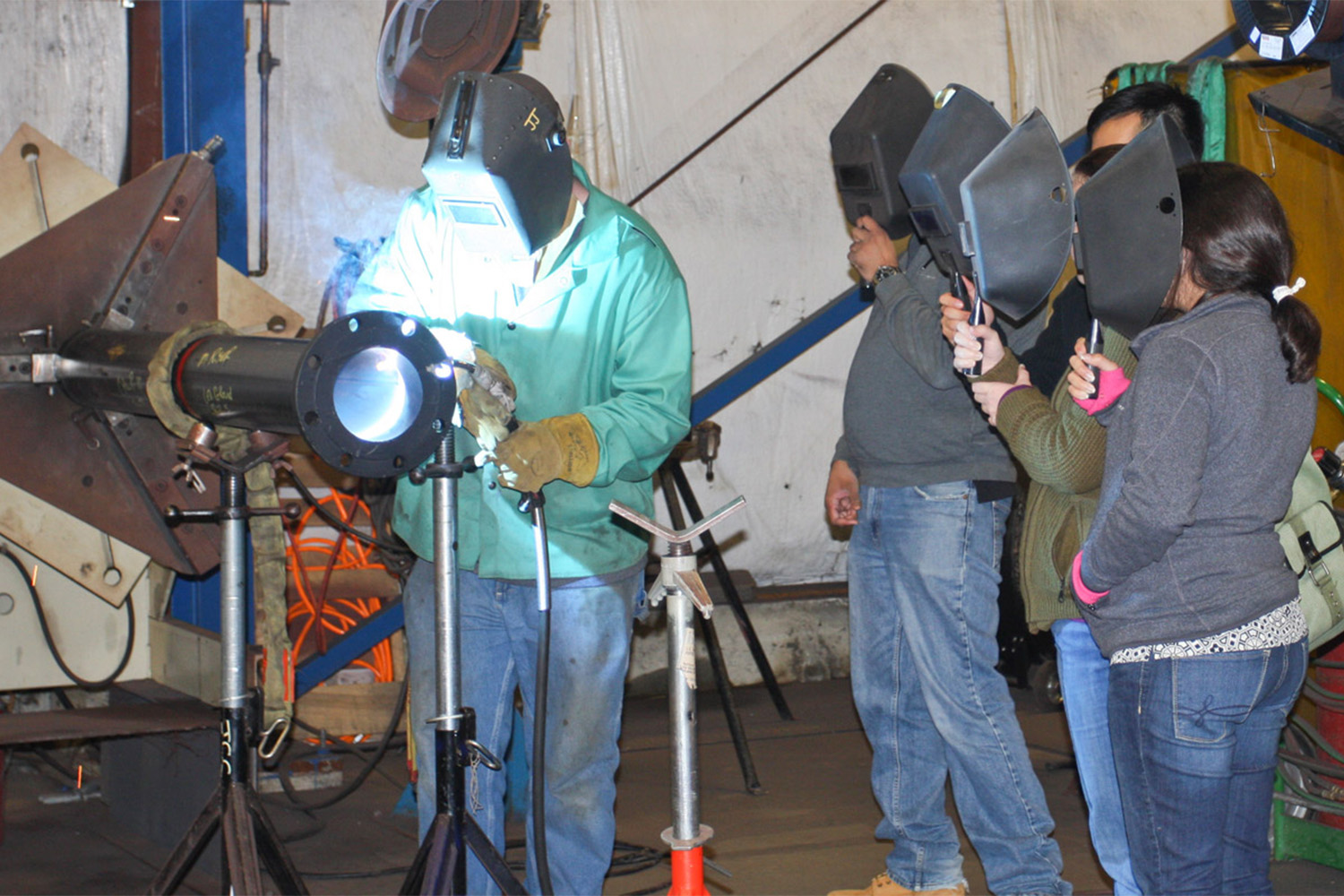 people wearing welding masks as they watch a demonstration 