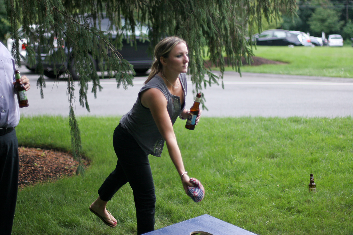 woman is leaning down, preparing to throw a sack into the cornhole