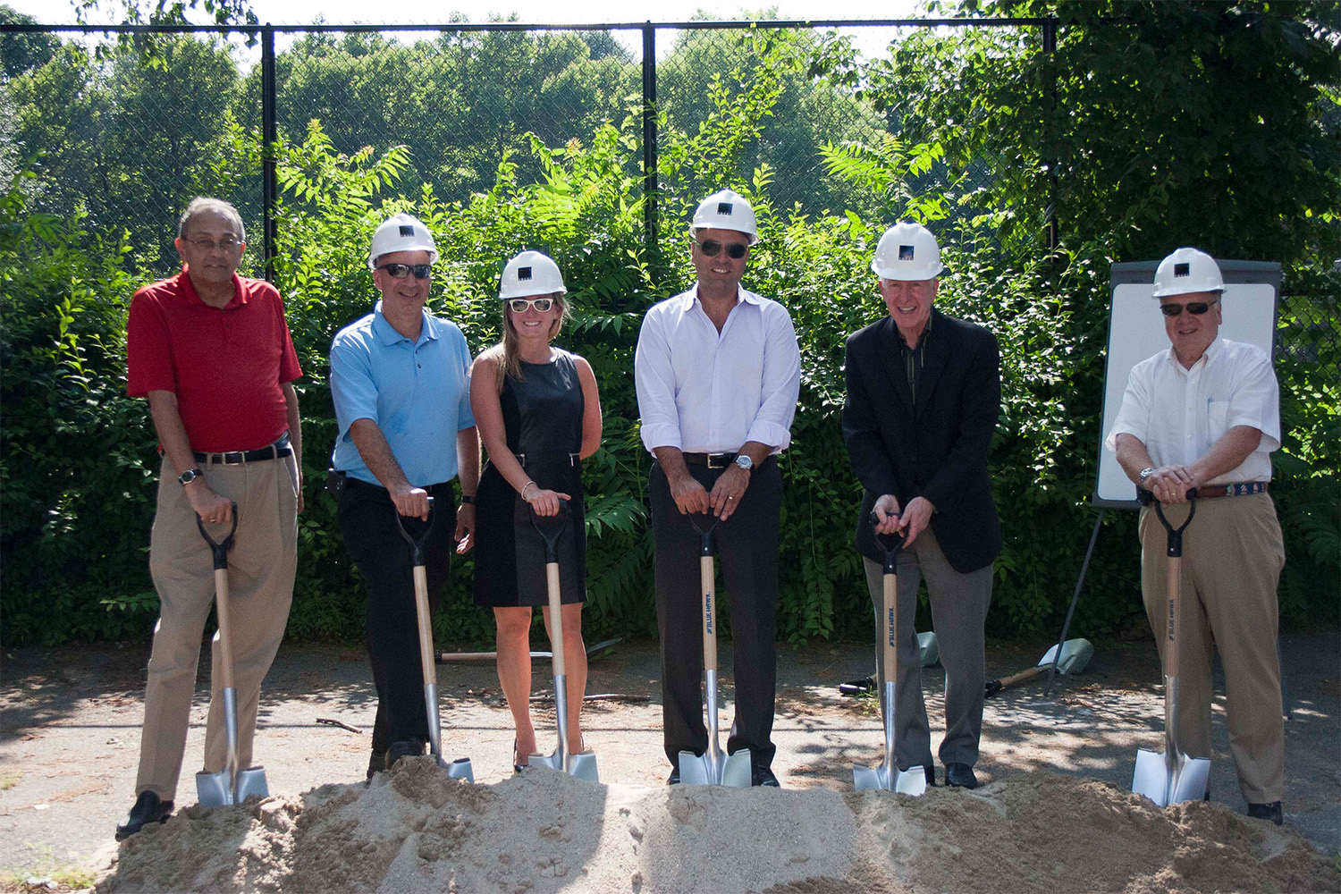 John Tocci with other Tocci representatives, holding shovels behind a big dirt pile 