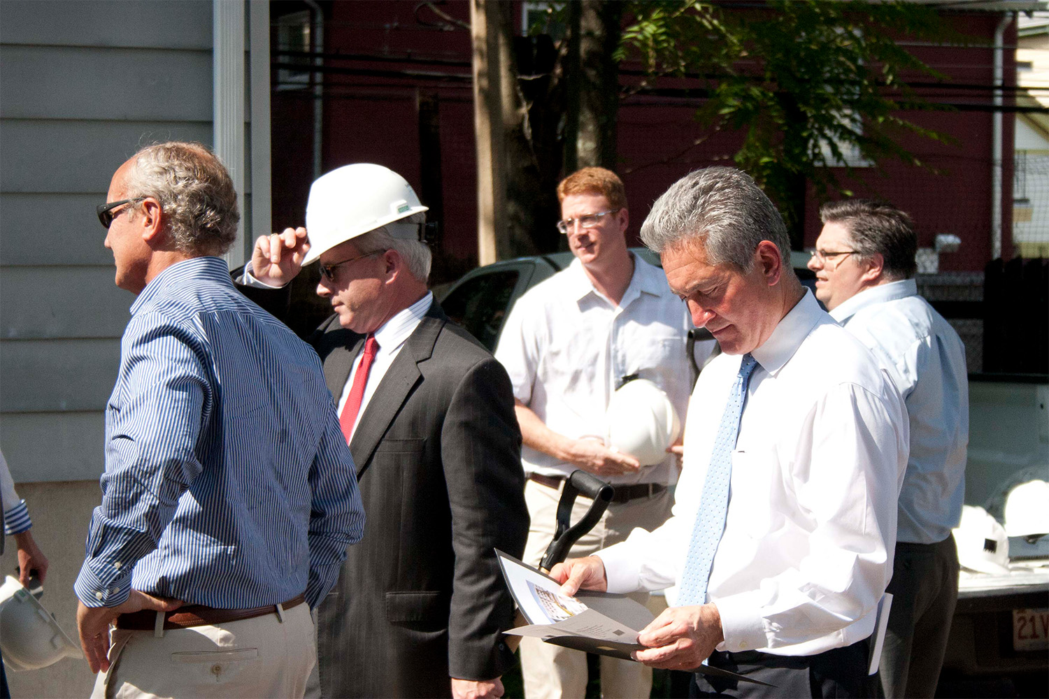 several overseers to the groundbreaking ceremony, onw man reading a piece of paper