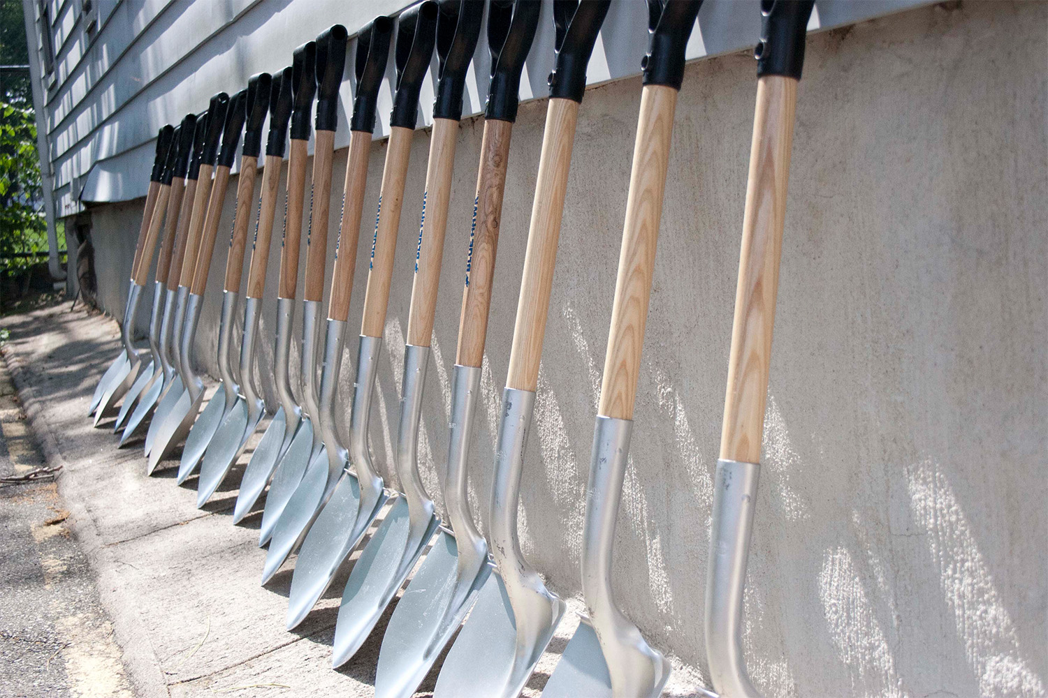 a line of shovels leaning against a building 