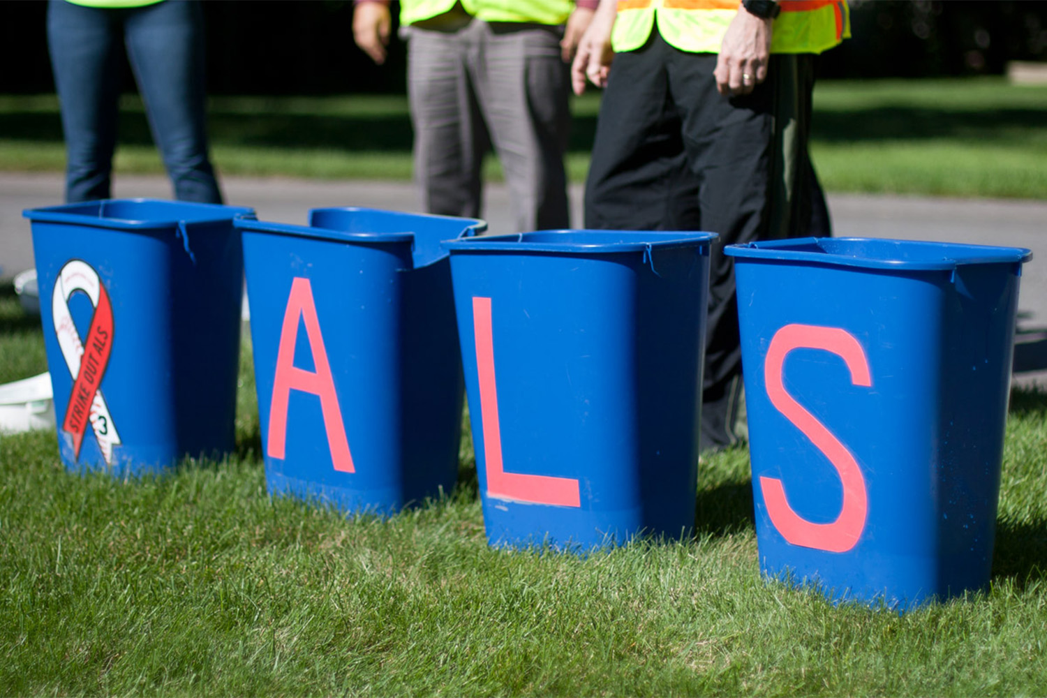 A row of 4 blu8e plastic buckets, with the letters "A, L, S" painted on them 