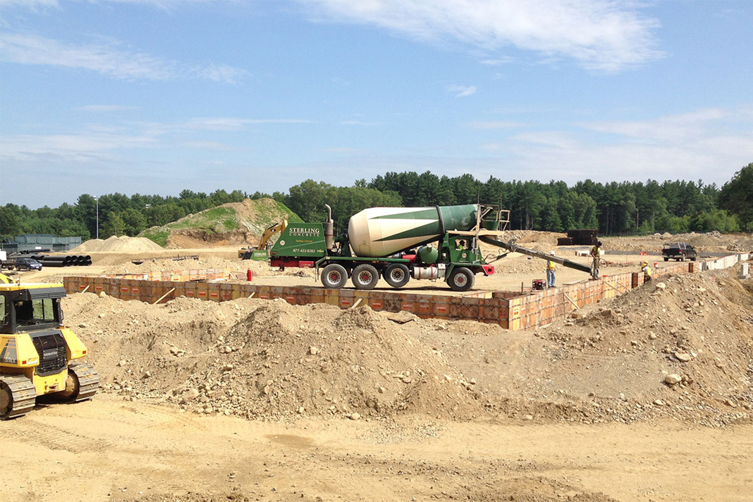 dirt pile at construction site, with a cement truck in the background 