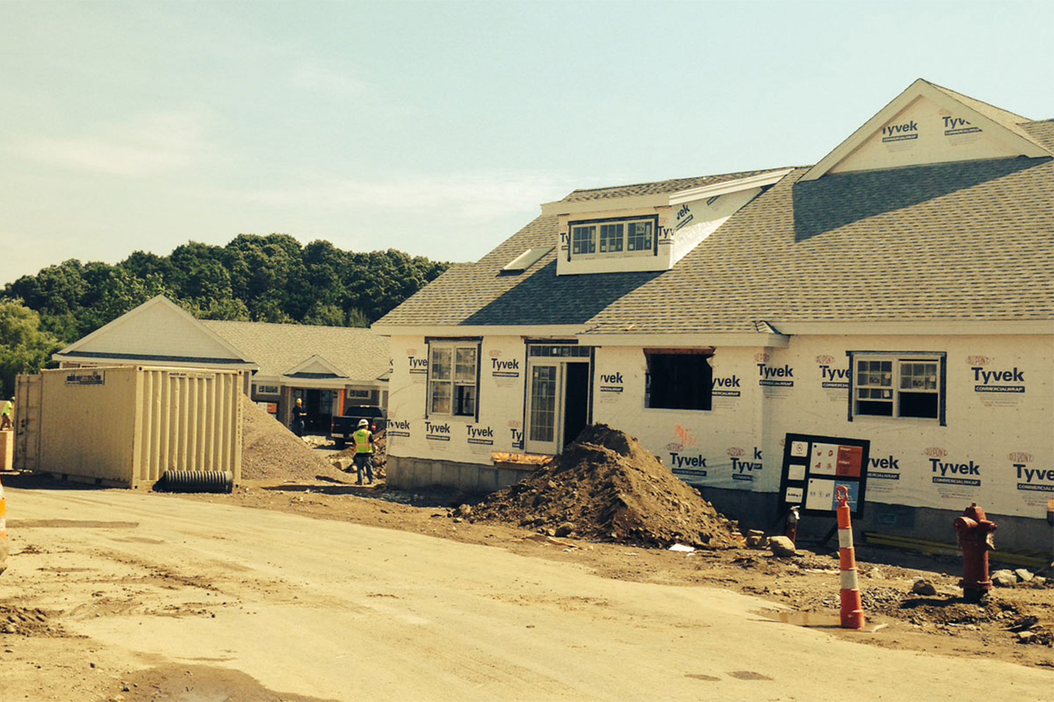 view of one house under construction, with a safety awareness sign leaning against it 