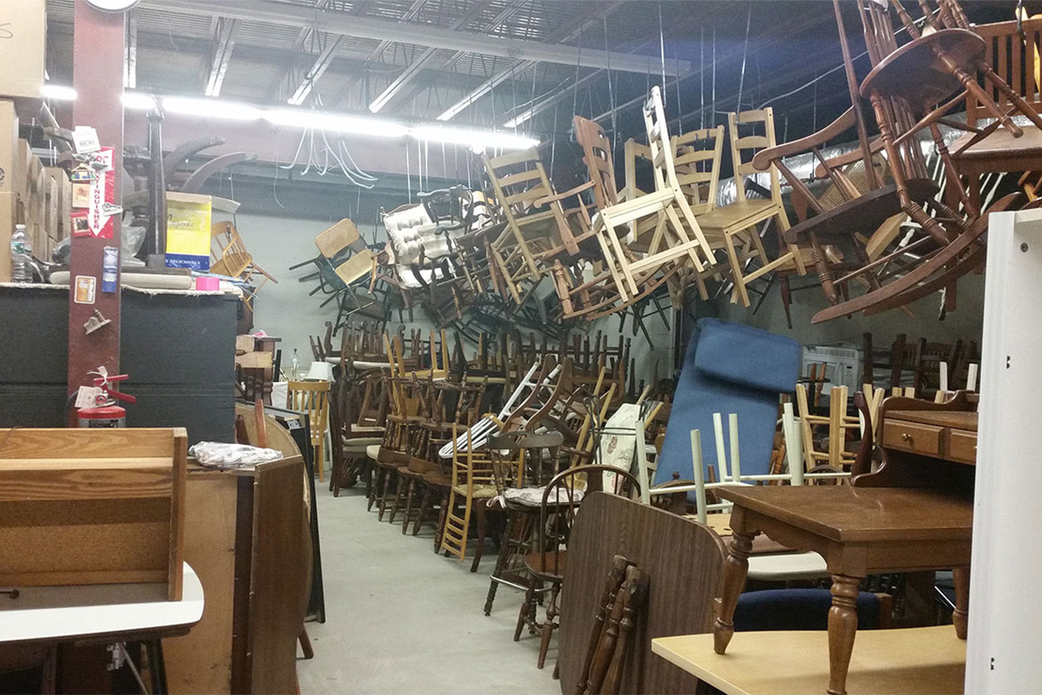 Inside the MOD warehouse: lots of wooden chairs hanging from the ceiling