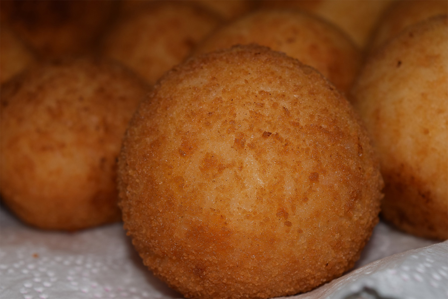 zoomed in view of fried arancini balls on a paper towel 