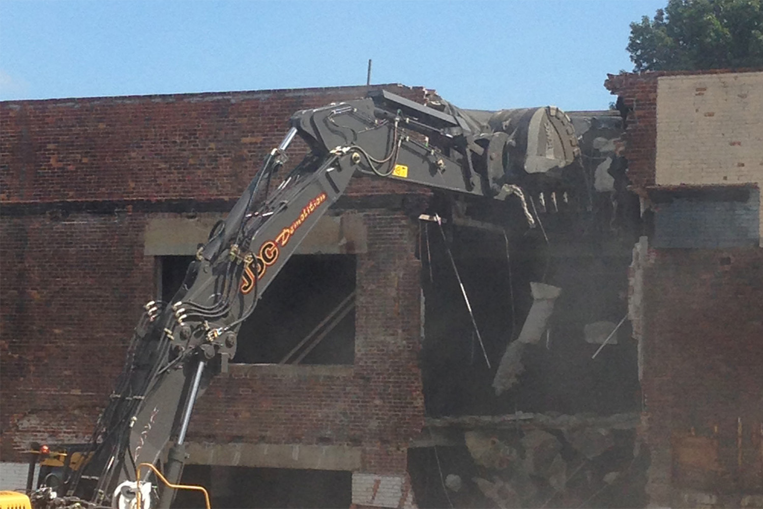 an excavator tearing down the building brick by brick.