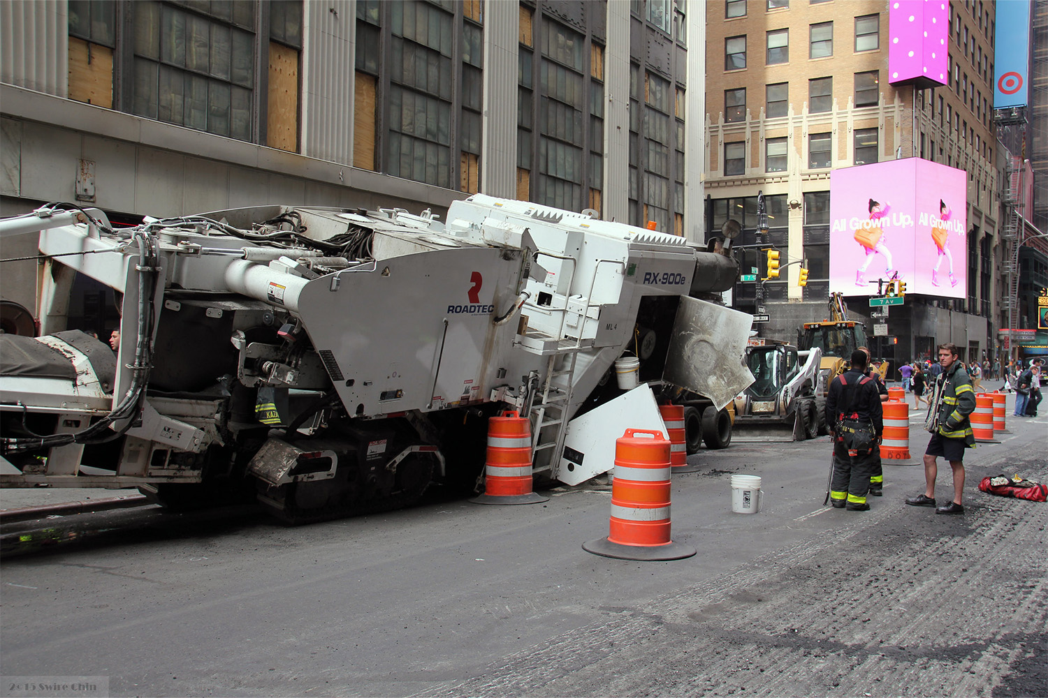 overseers looking at turned over construction vehicle at jobsite