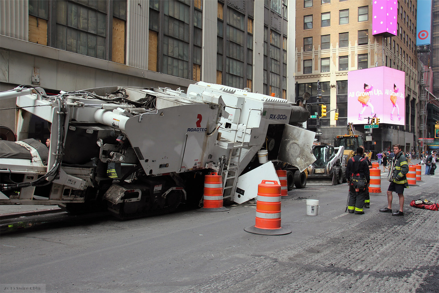 overseers looking at turned over construction vehicle at jobsite 