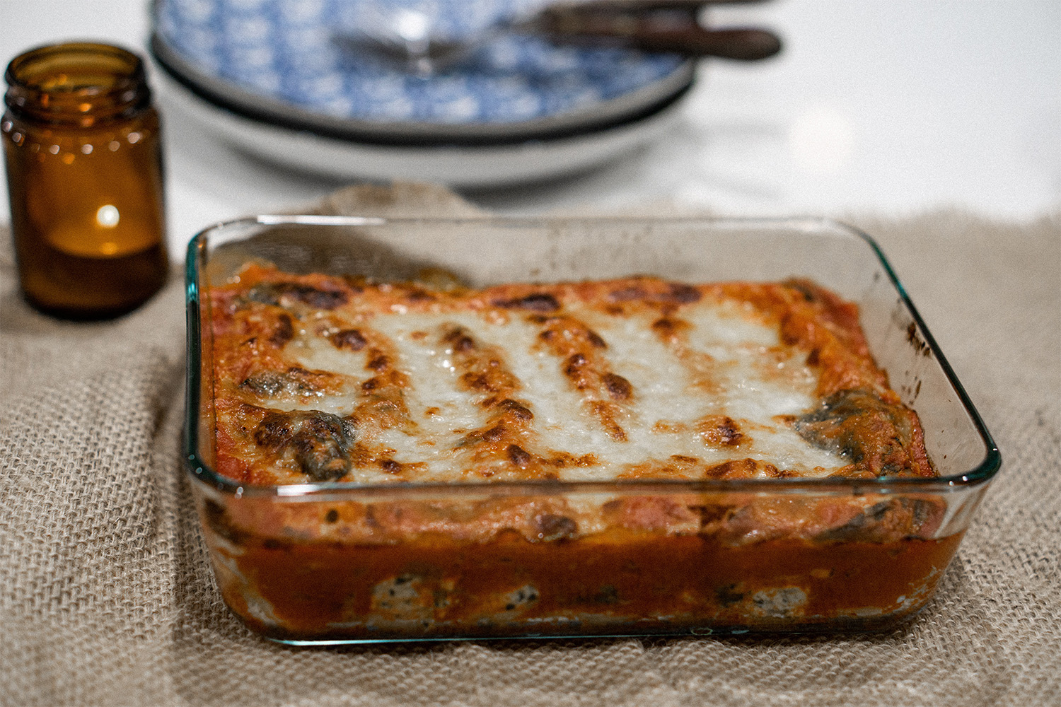 lasagna in a glass dish, on top of burlap table cover 