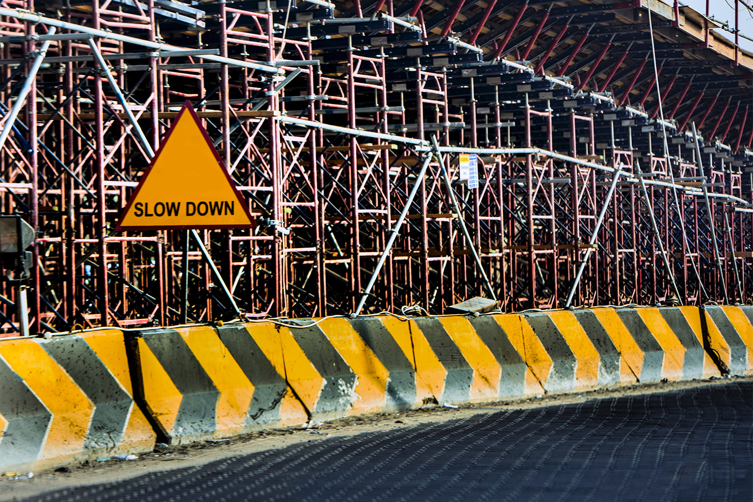 yellow and black road concrete block, with slow-down sign in front 