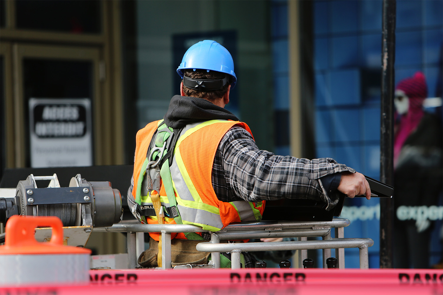 man in an orange PPE vest, on top on a lift 