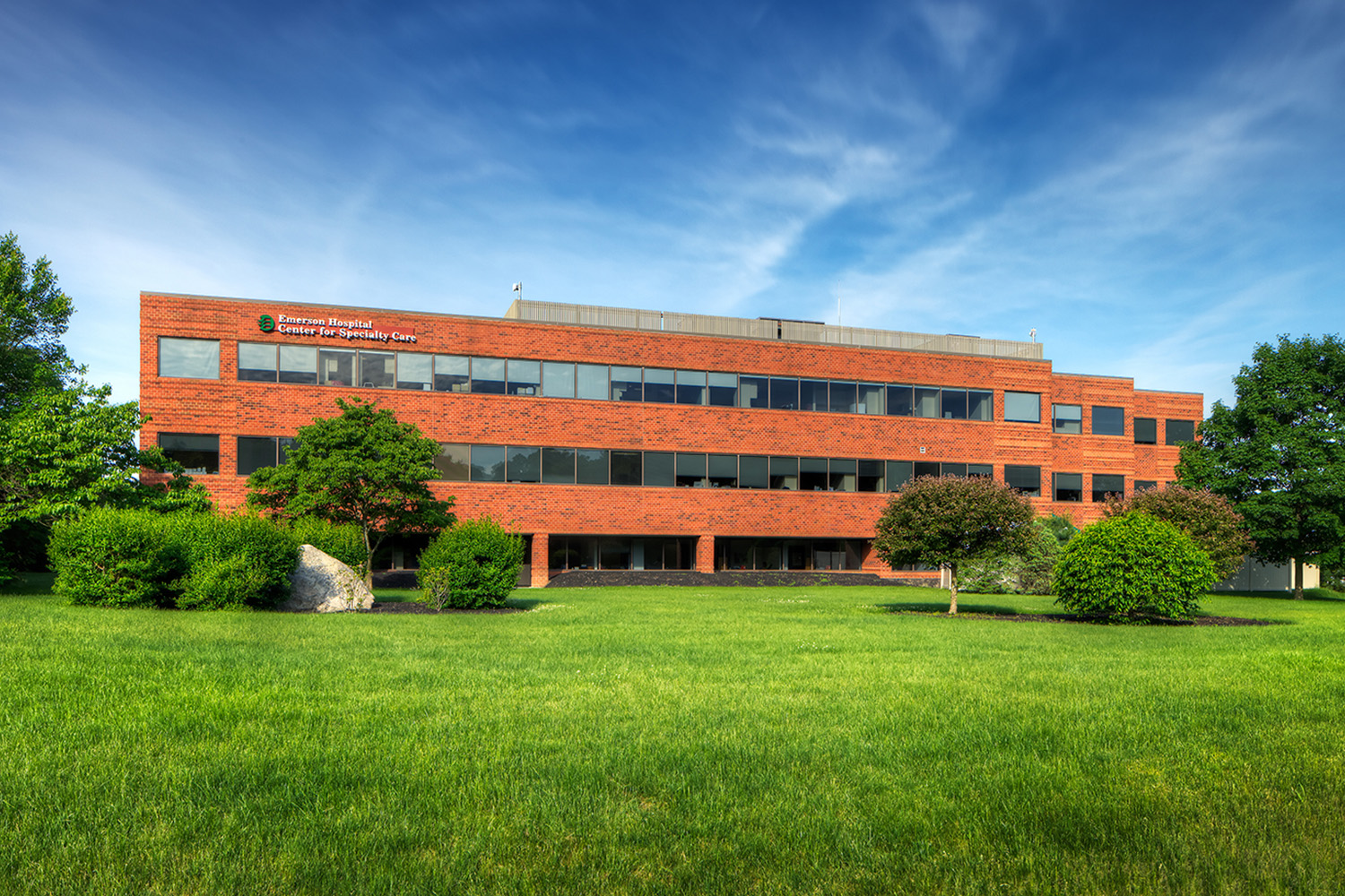 front exterior of the Emerson Center for Specialty Care, seen from across a lush green field 