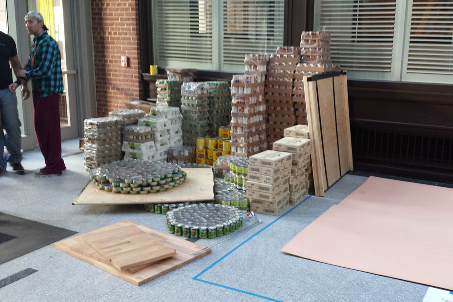 over a hundred cans of food on a large sheet of cardboard