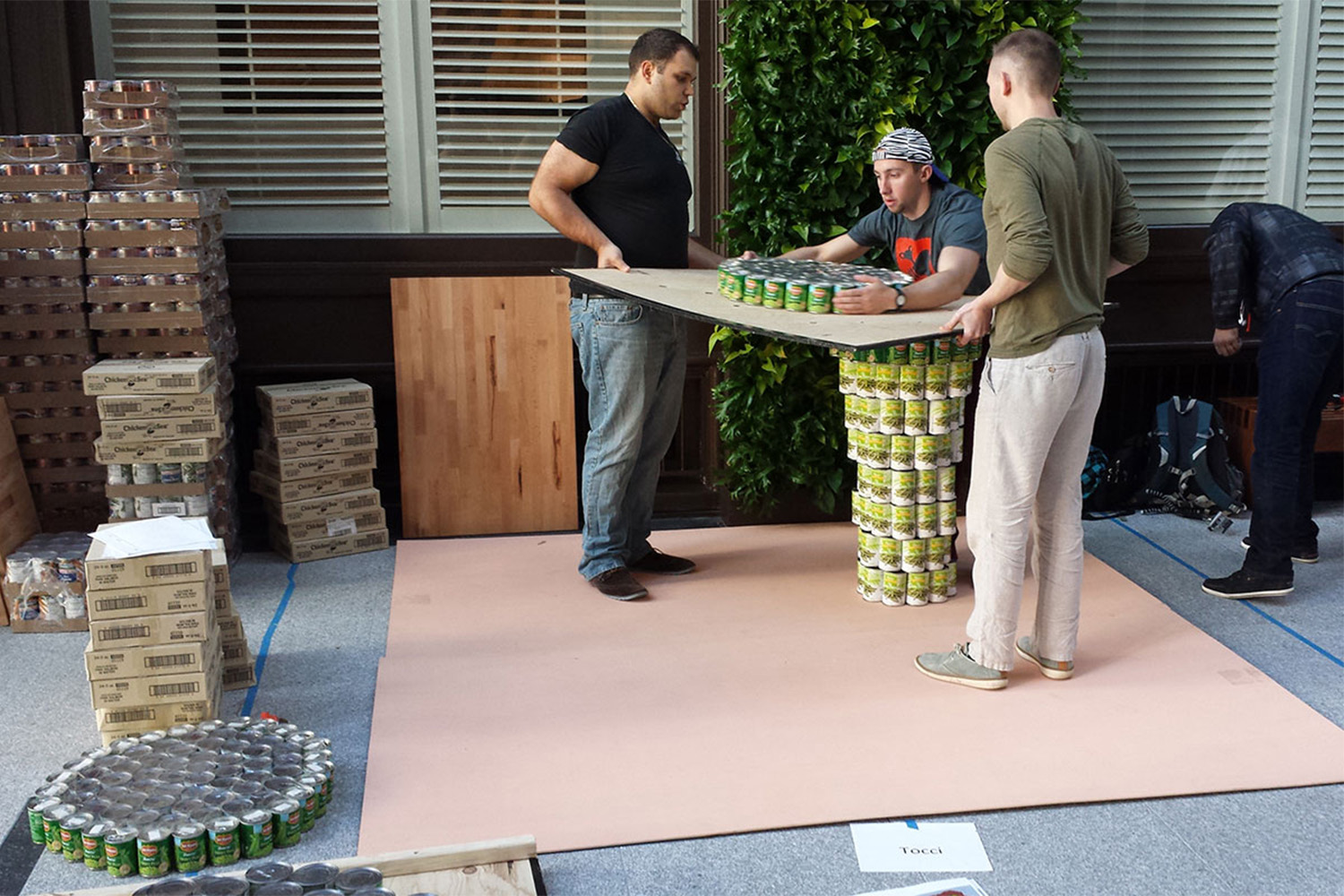 Tocci employees build a structure out of cans of food 