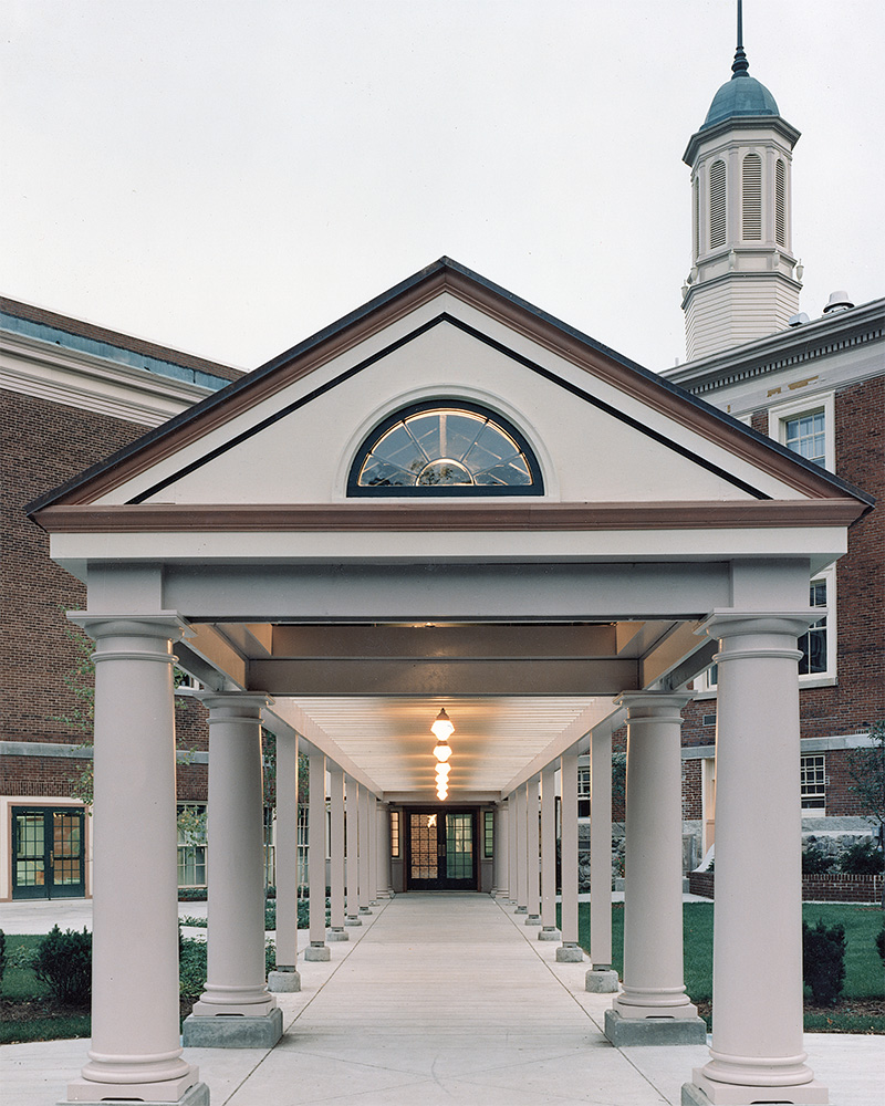 frontal view of entry way to the apartment complex, with white pillars on both sides of the walkway 