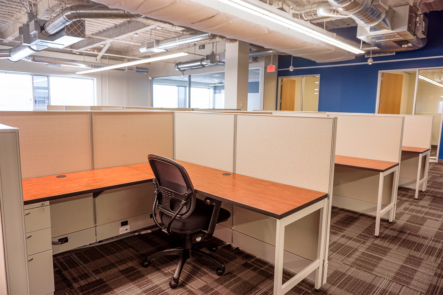 Sovos office area, with wooden tables and tan cubicle dividers 