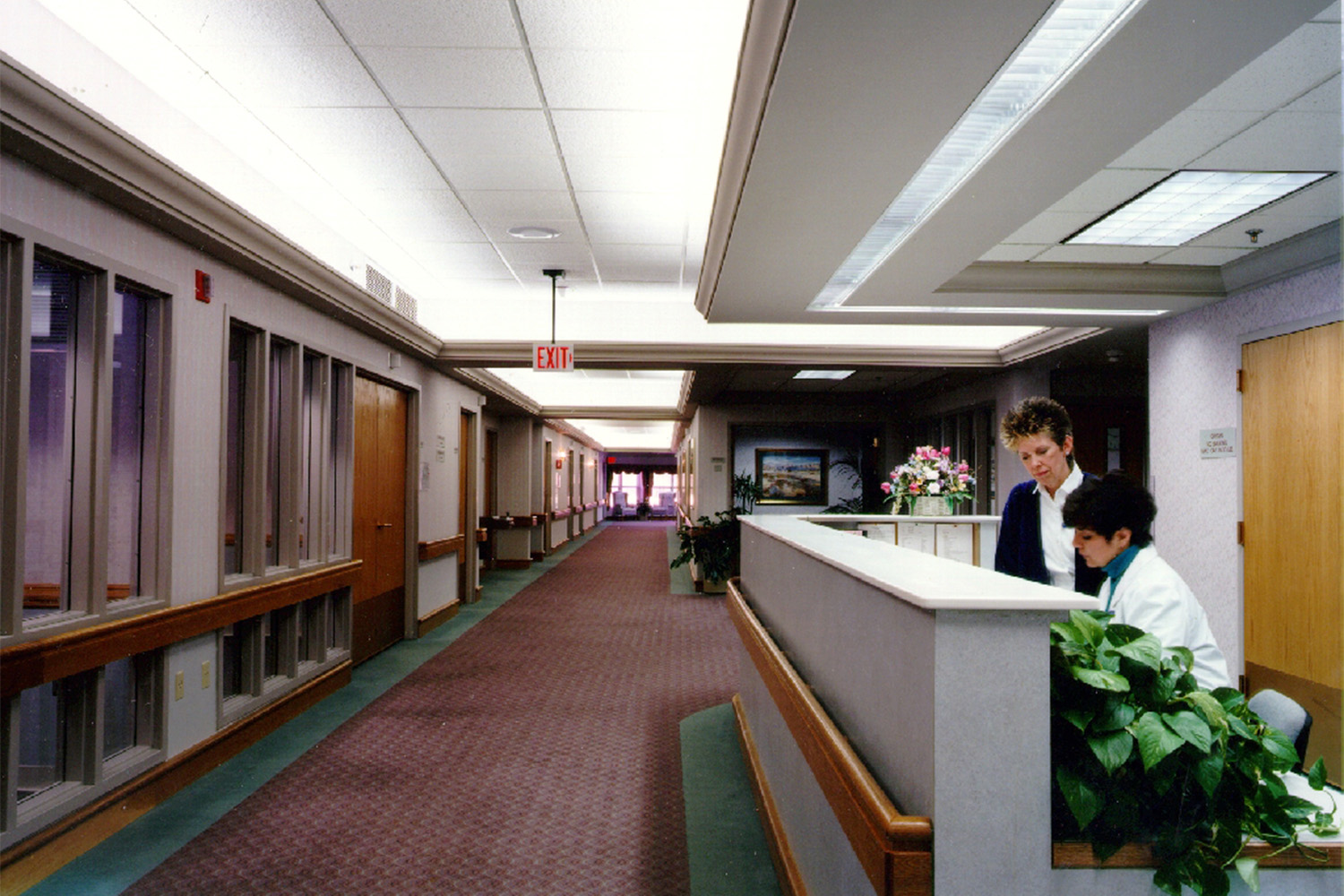 Longview of hallway at Alzheimer's care facility, with nurses working by desk