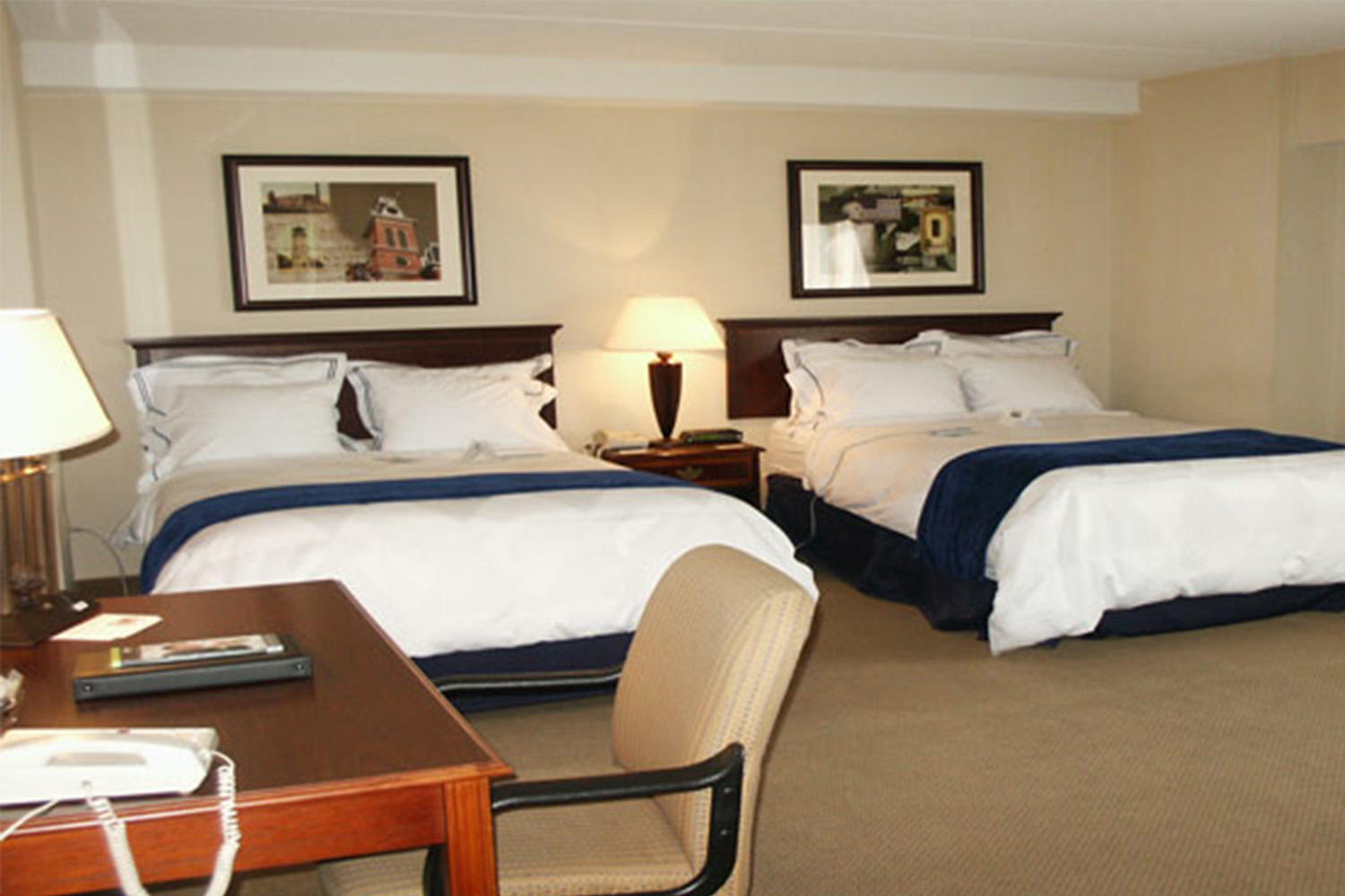 hotel room with two beds, with a photo mounted above each wall 