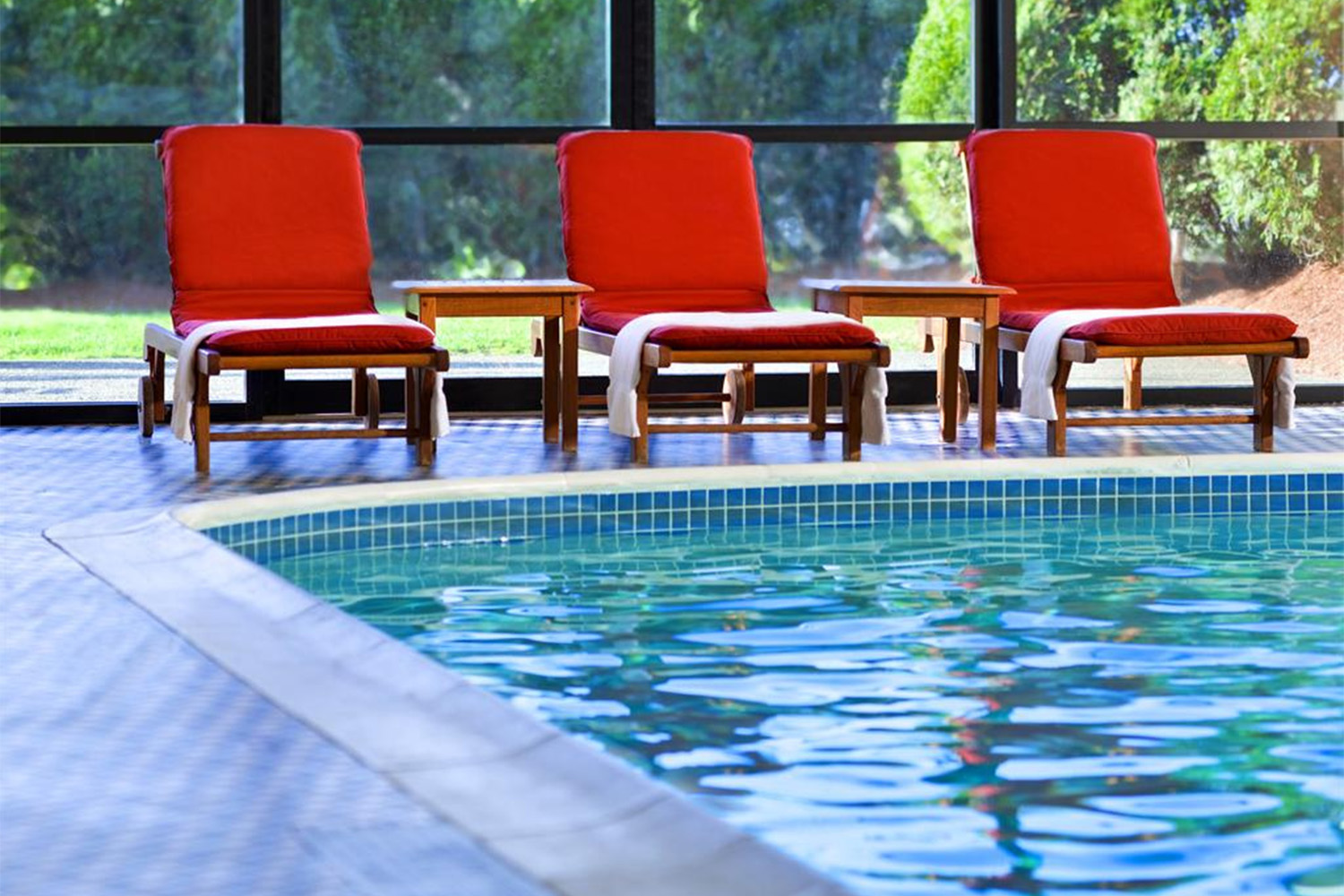indoor swimming pool complete with red chairs and walls made of windows 