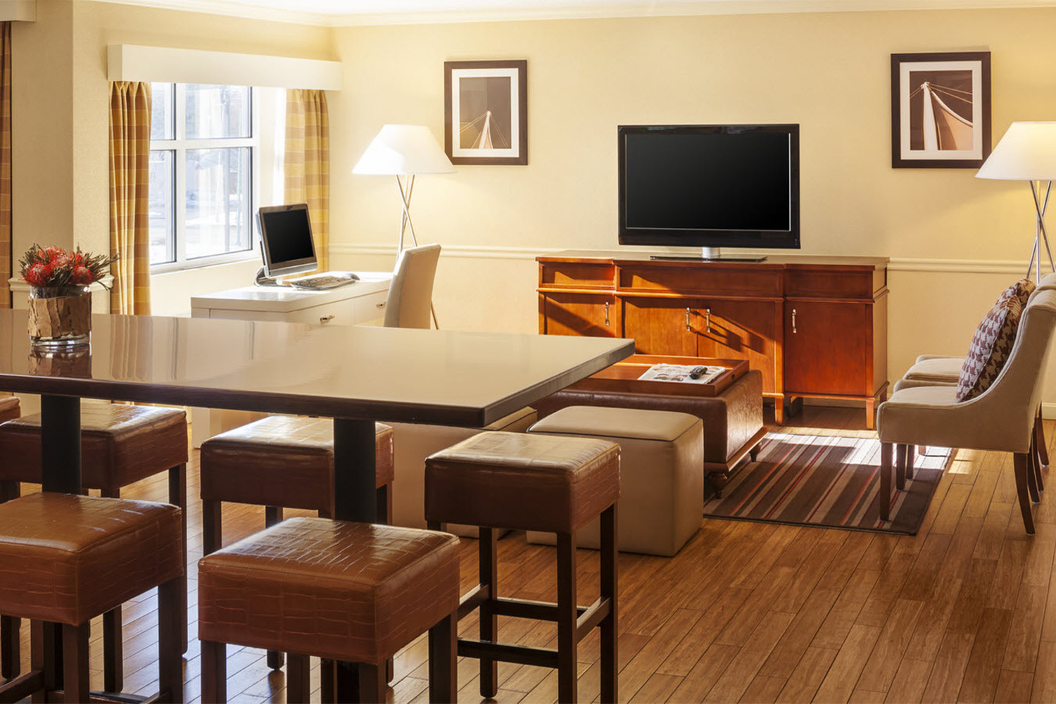 hotel room with TV, and wooden table near window 