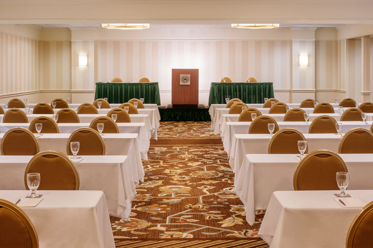 conference room with white covers on all the tables, and tan chairs