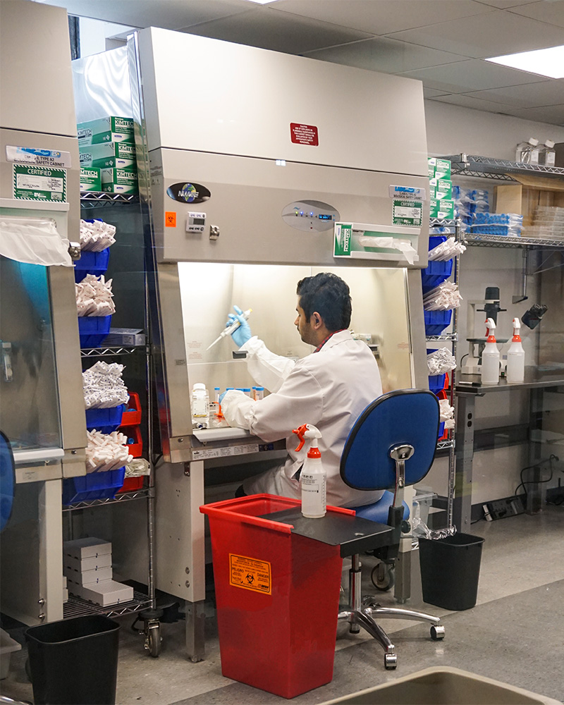 a man using a medical pipette by chemical fume chamber 