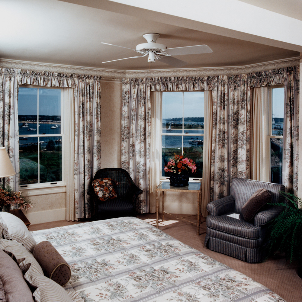 bedroom, with view of the dusk sky outside the three windows 