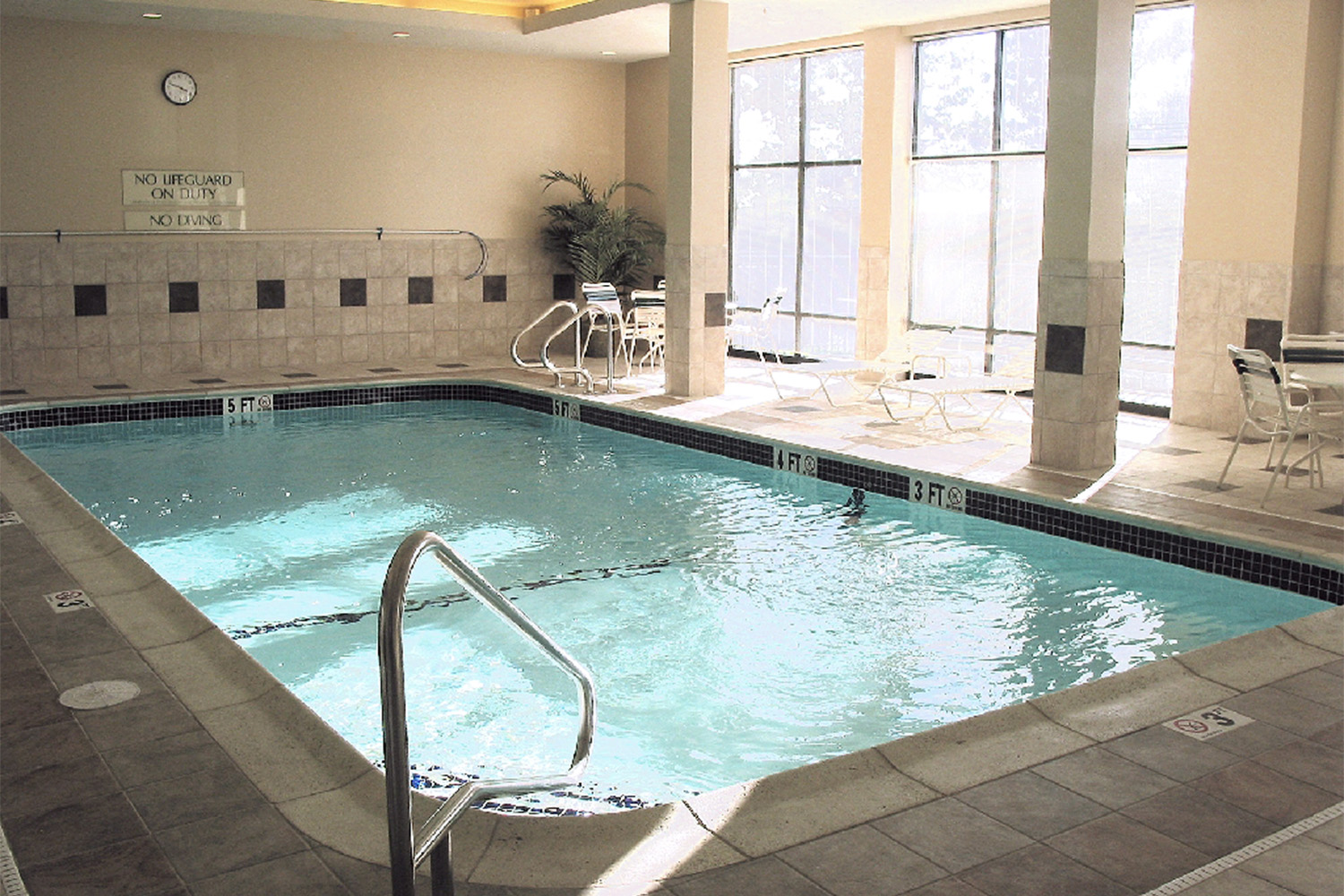 Longview of swimming pool, next to brightly lit windows. 