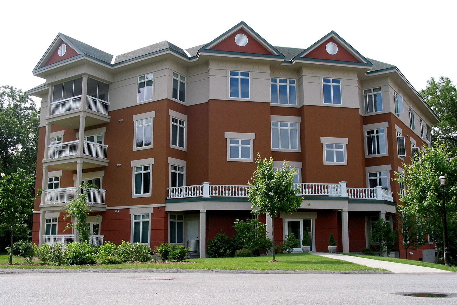 red building with tan detailing at the top, nestled in-between trees