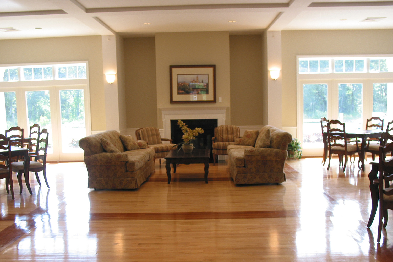 recreation area with couches parked in front of fireplaces, and several black metal dining chairs and tables to either side 