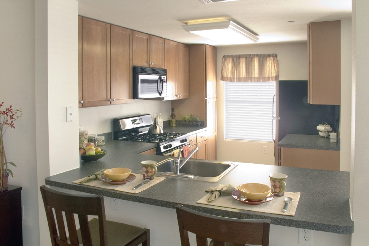 Kitchen area with black bar stools an black granite countertops 