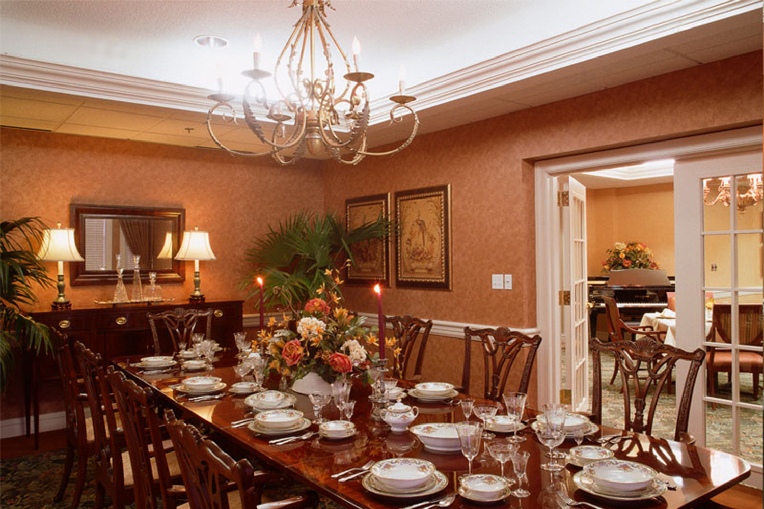 long mahogany wooden table with chandelier hanging overhead 