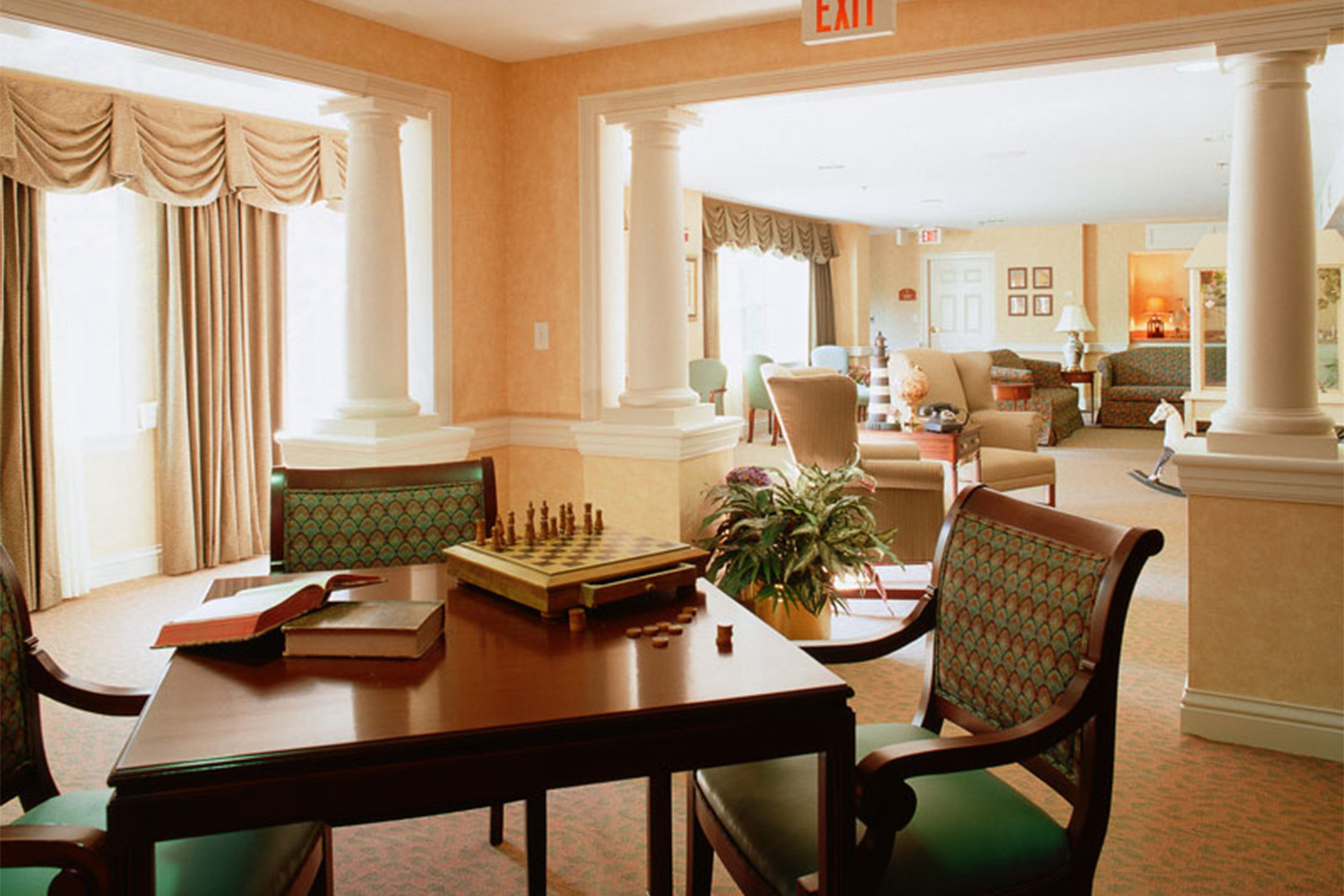 sunlit room with mahogany chairs and green cushioning 