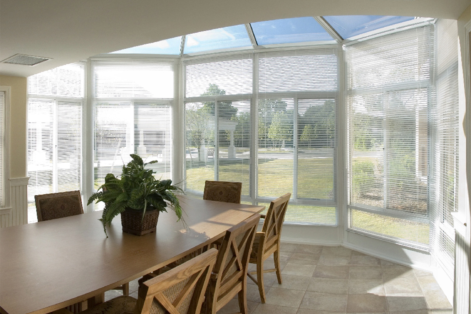 indoor patios, with a wall made of windows, and long wooden table beneath 