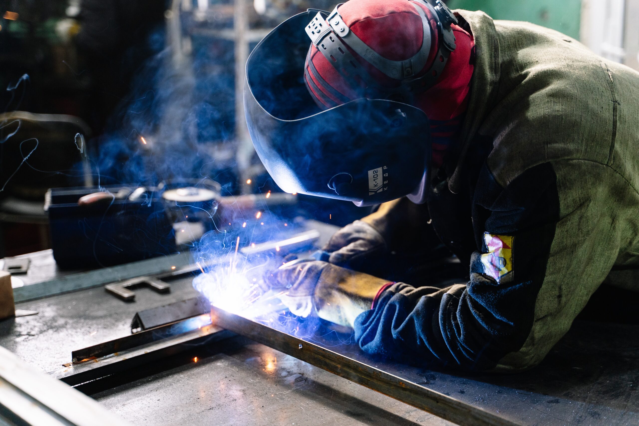 a man welding, with blue sparks near his hands