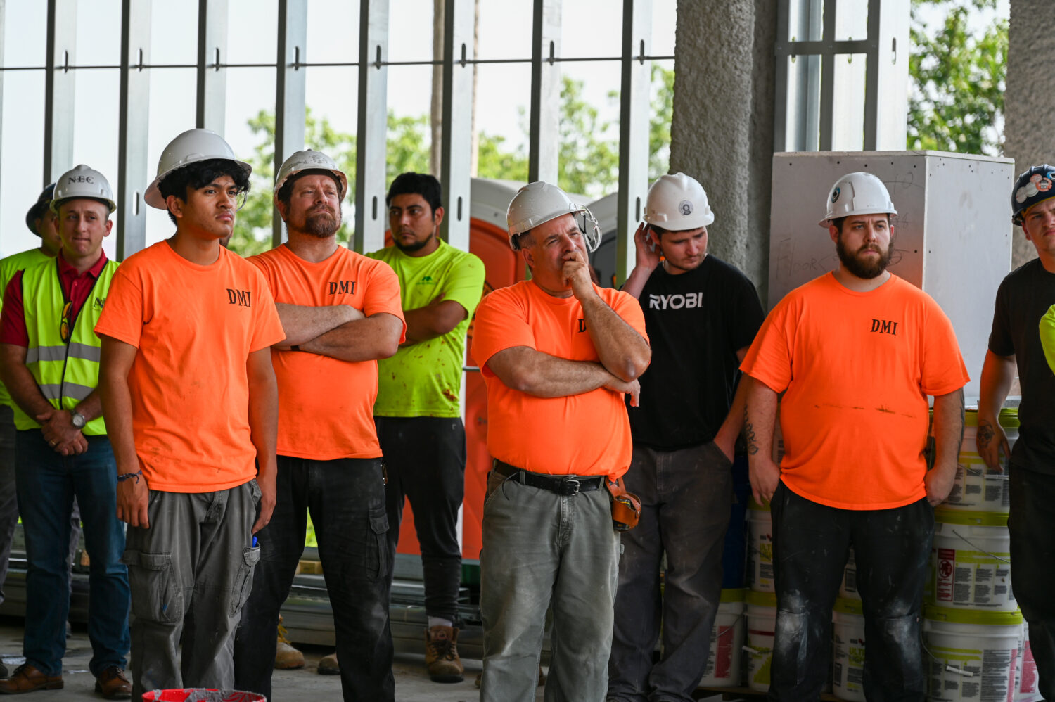 construction workers in orange shirts listening to John Tocci's speech 