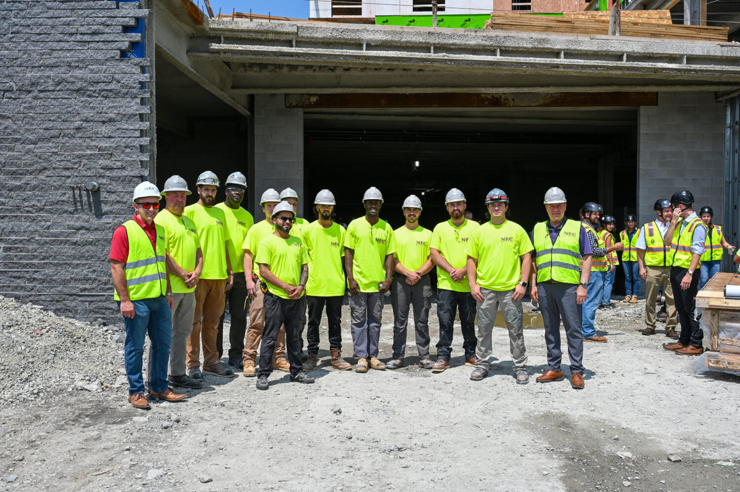 construction workers wearing safety yellow shirts, posing for photo at 1515 Topping Off ceremony 