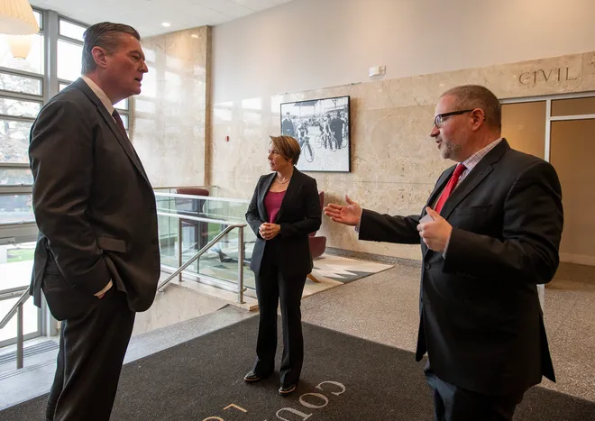 Photo of three people in business attire talking in a marble courthouse lobby