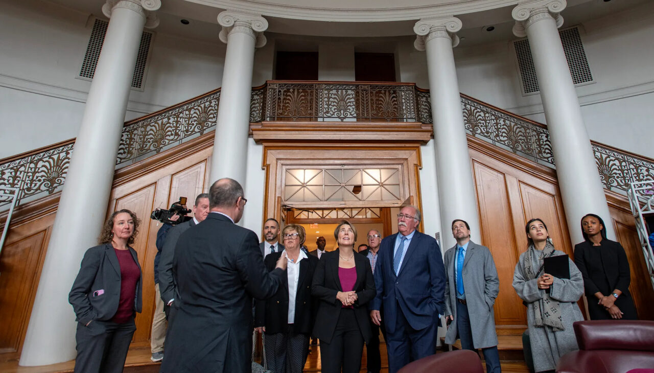 Photo of a group of people gathered in the domed rotunda of Courthouse Lofts, looking up at the ceiling during a press tour.