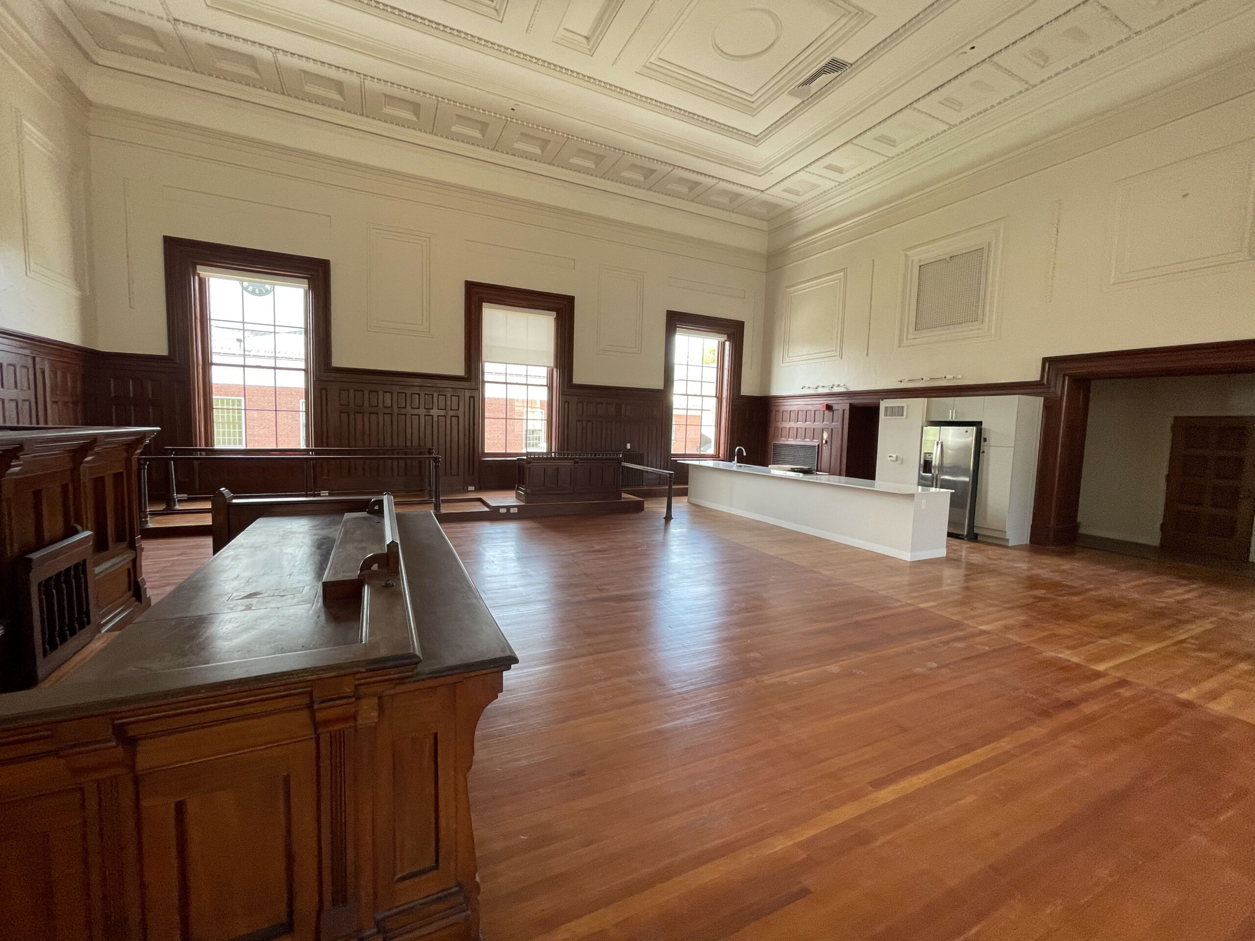 A converted courtroom residence with original wood paneling and judge's bench beside a new kitchen.
